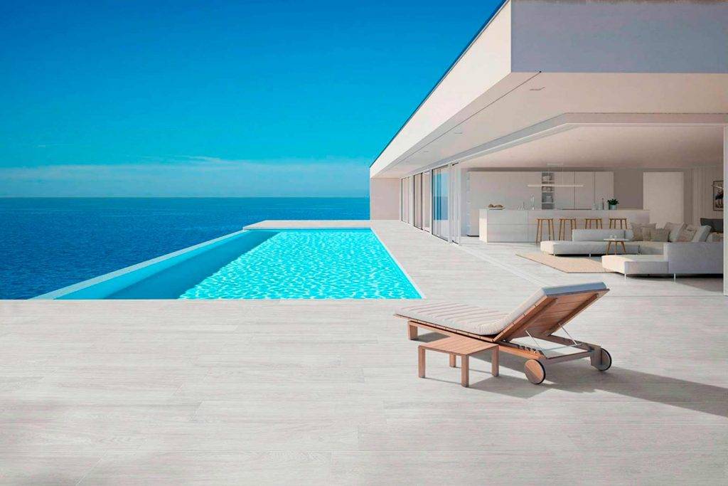 El porcelánico imitación madera Banak blanco es ideal para combinar con los azulejos de tu piscina.